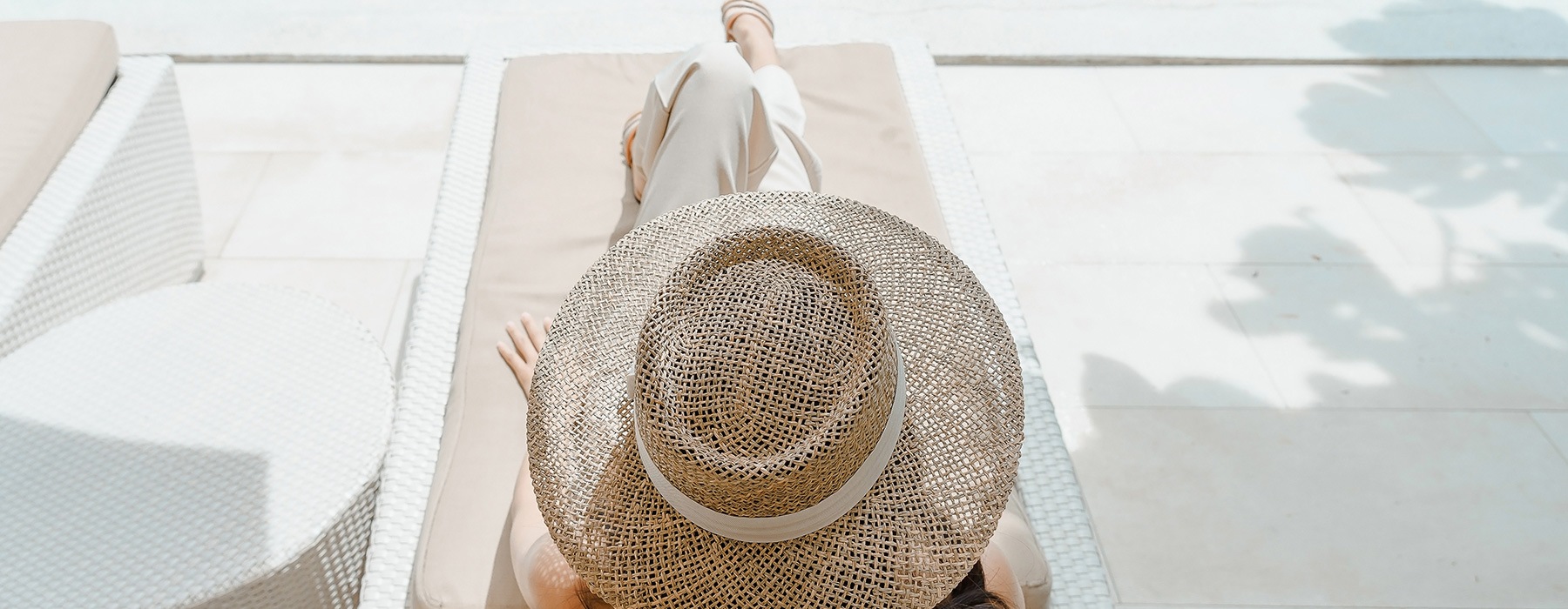 lifestyle image of a woman laying on a reclining chair beside the pool